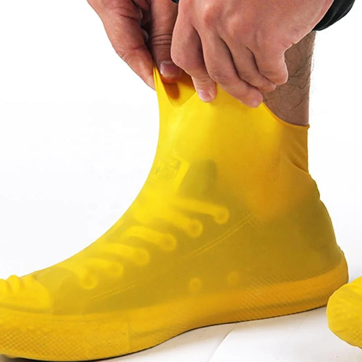 Person putting on yellow waterproof silicone shoe covers over sneakers