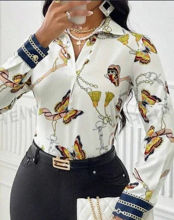 White button-up blouse with colorful butterfly and chain print, paired with black pants and gold belt