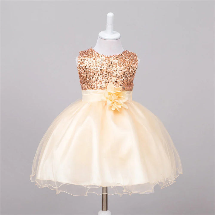 Cream tulle baby girl dress with gold sequin bodice and floral waist detail on mannequin