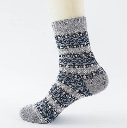 Gray and blue patterned wool sock on a mannequin foot with ribbed cuff and textured knit design