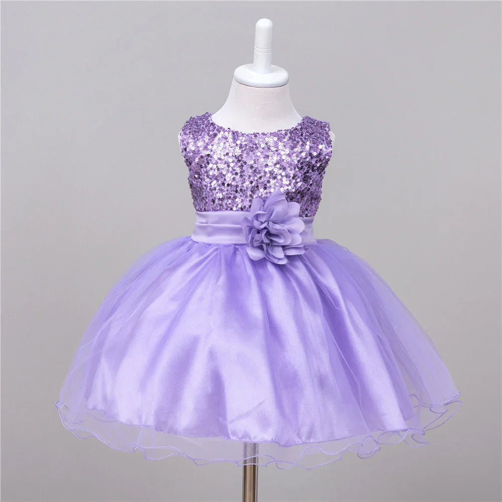Purple toddler dress with sequin bodice, satin waistband, flower accent, and tulle skirt on mannequin