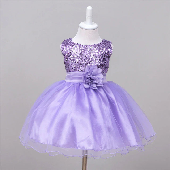 Purple toddler dress with sequin bodice, satin waistband, flower accent, and tulle skirt on mannequin