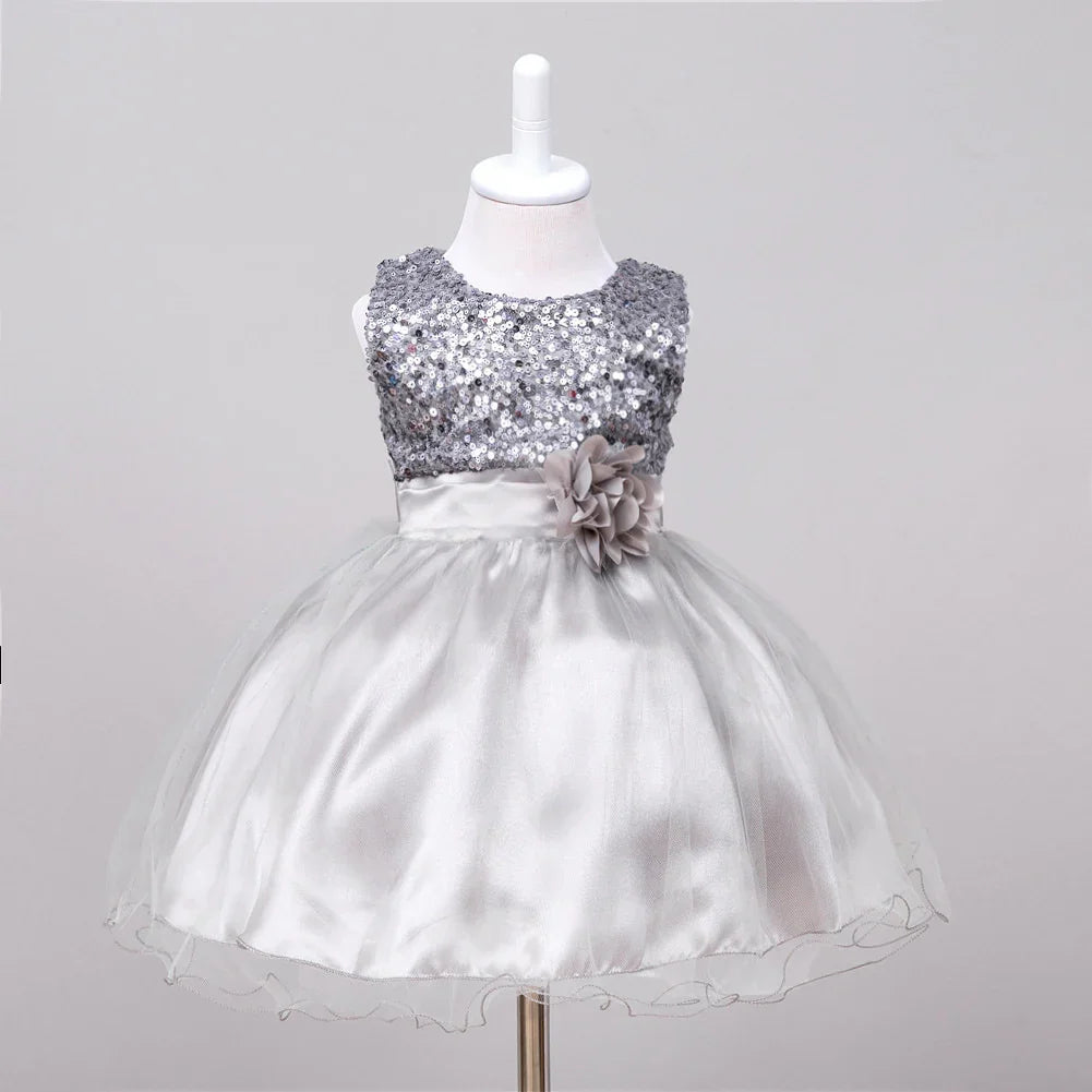 Silver sequin sleeveless baby dress with satin skirt and floral waist embellishment on mannequin