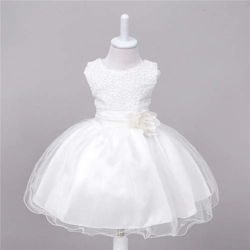 White sleeveless baby dress with lace bodice and tulle skirt featuring a floral sash detail