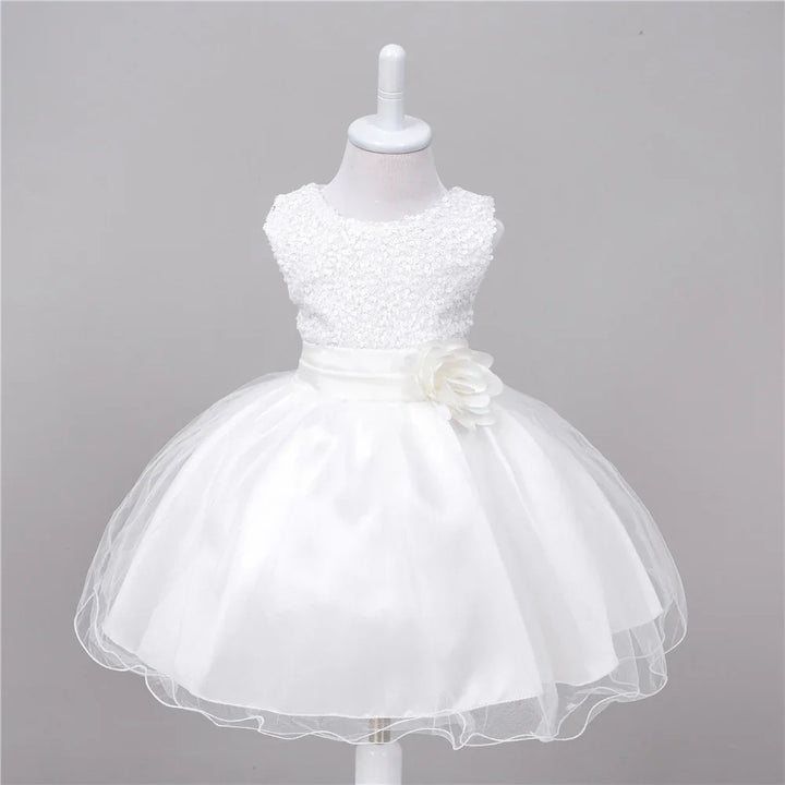 White sleeveless baby dress with lace bodice and tulle skirt featuring a floral sash detail