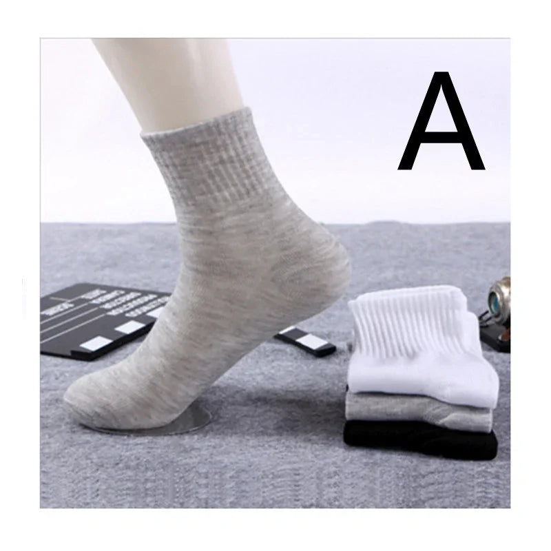 Light gray ribbed ankle sock on mannequin foot with folded white, gray, and black socks nearby