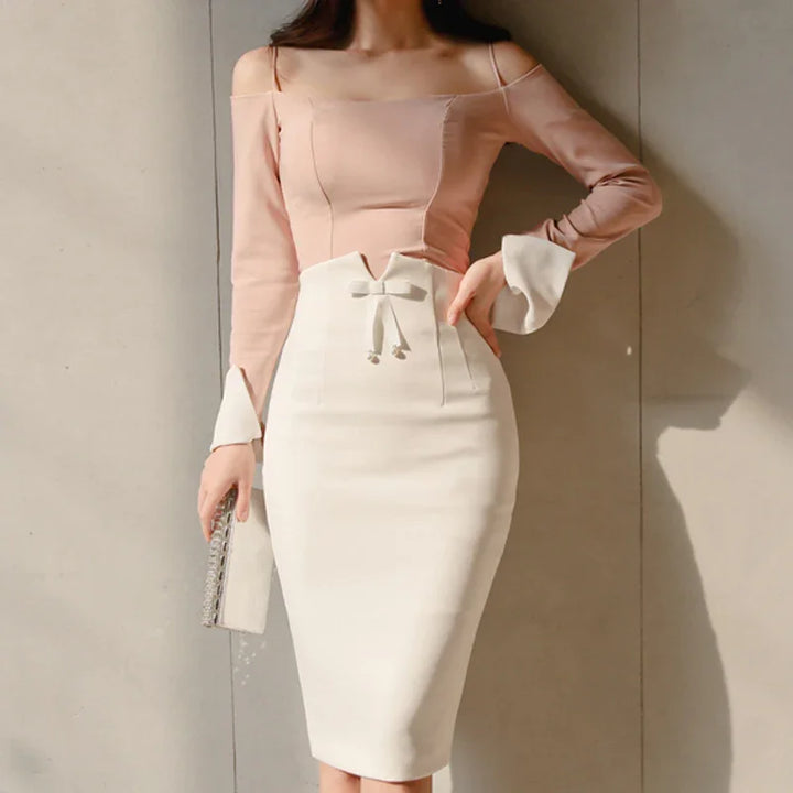 Woman wearing two-tone pink and white fitted midi dress with bow detail and holding silver clutch