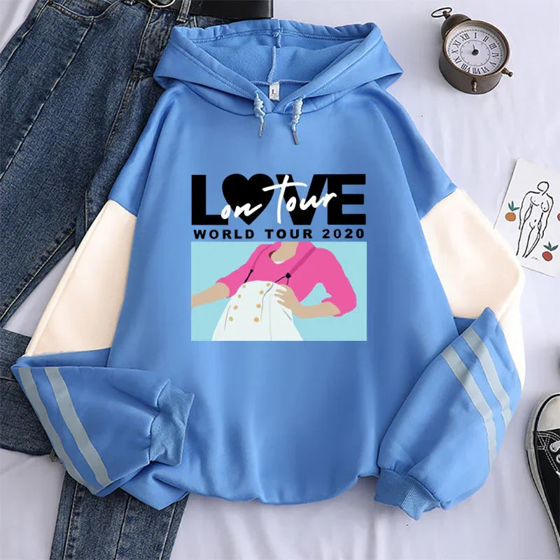 Blue hooded sweatshirt with color block sleeves, graphic design saying LOVE on Tour World Tour 2020, paired with denim jeans