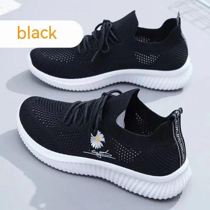 Black lightweight knit sneakers with white rubber soles and embroidered daisy detail