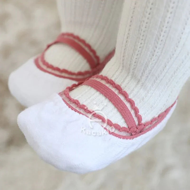 Close-up of white baby socks with pink scalloped trim and textured knit pattern