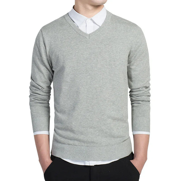 Man wearing light gray V-neck sweater over white dress shirt with black pants