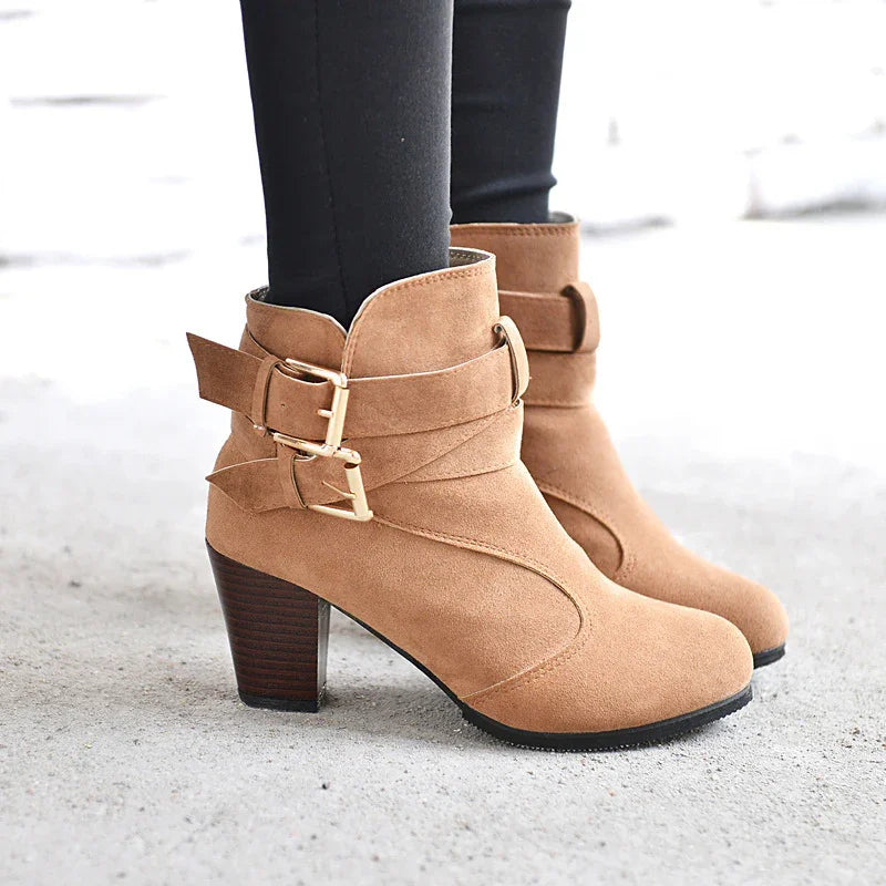 Tan suede ankle boots with gold buckles and stacked heels worn with black leggings