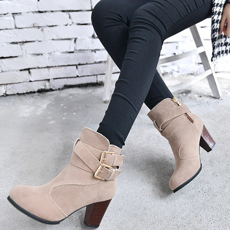 Woman wearing beige suede ankle boots with gold buckles and block heels with black leggings