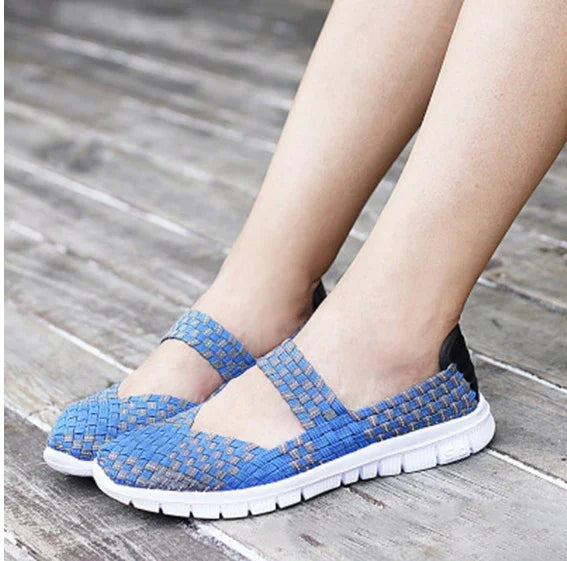 Blue woven slip-on shoes with white soles worn on wooden floor