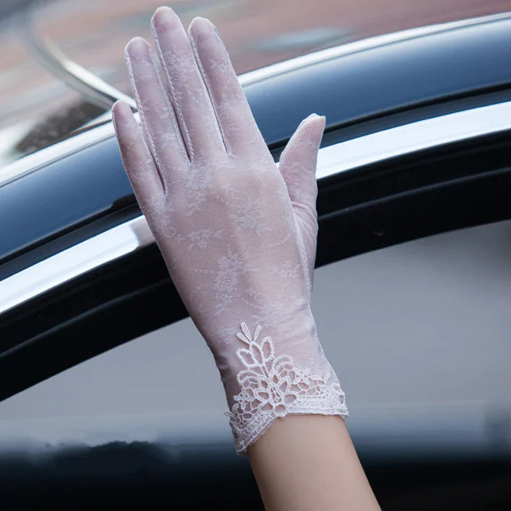 Hand wearing delicate white lace gloves raised outside a black car window