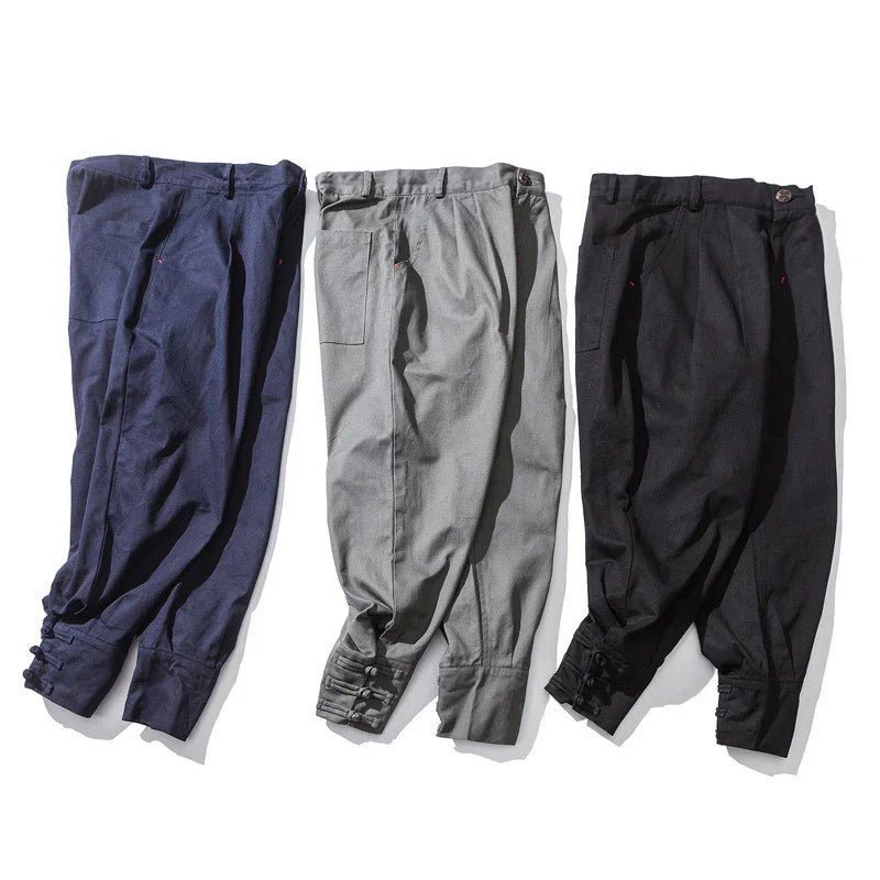 Three pairs of tailored pants in navy, gray, and black with buttoned cuffs on white background