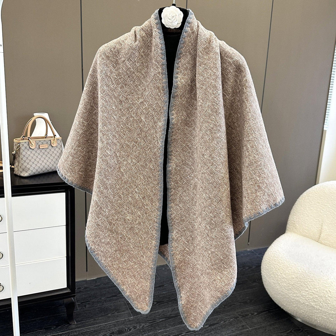 Beige textured woolen cape with gray trim on mannequin in modern room with handbag and chair