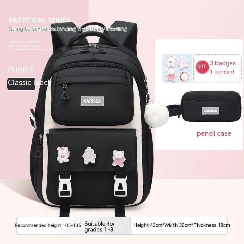 Classic black Karissa backpack with front badges and white pompom keychain, suitable for grades 1-3