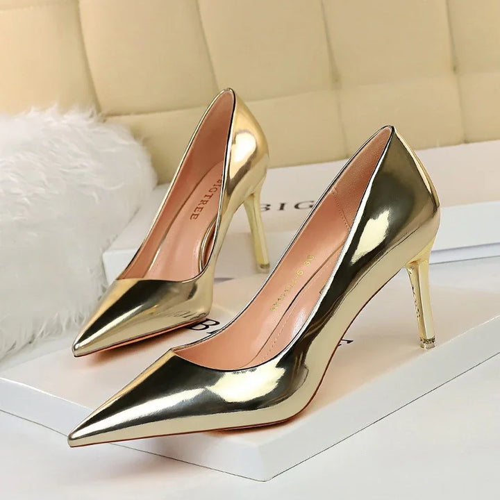 Pair of shiny gold high heel stiletto shoes on white boxes in a stylish indoor setting