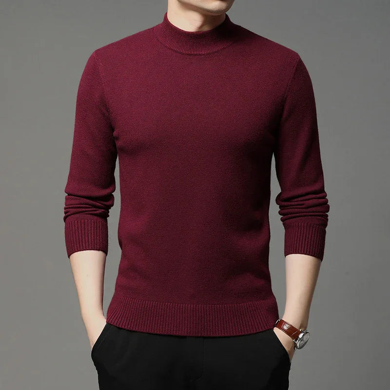 Man wearing a burgundy long sleeve mock neck sweater with black pants and brown wristwatch