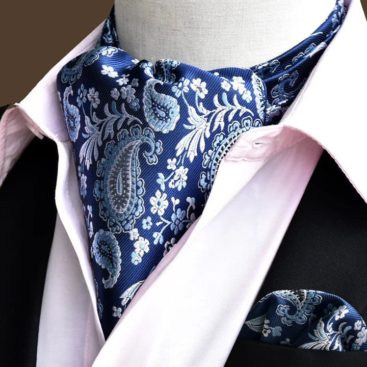 Close-up of blue paisley floral silk cravat and matching pocket square on pink dress shirt and black suit