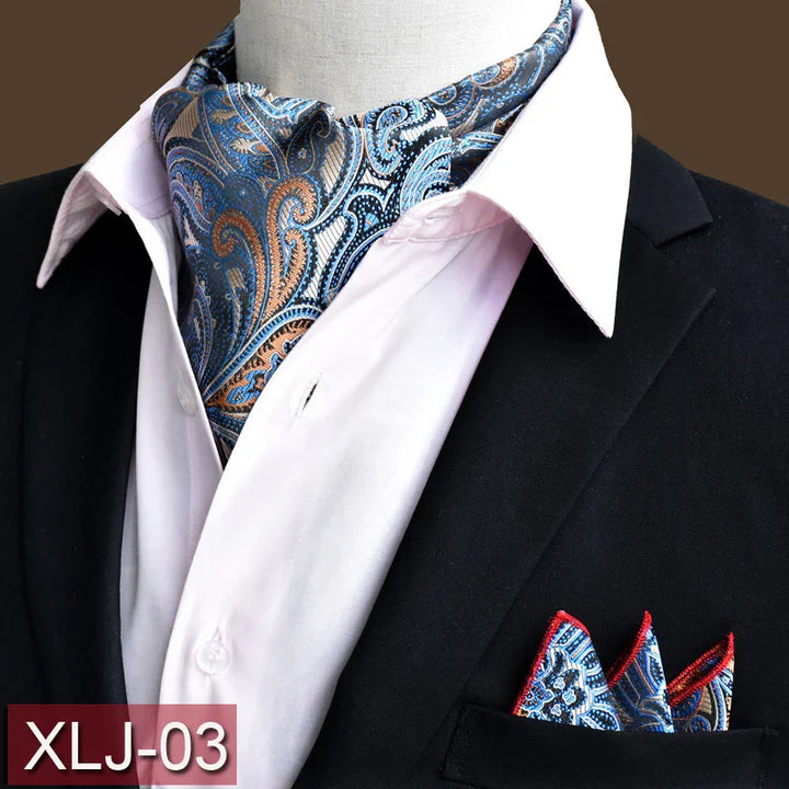 Men's black suit jacket with white shirt, blue paisley ascot tie and matching pocket square