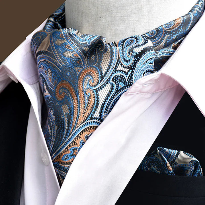 Blue and orange paisley patterned ascot tie paired with white shirt and black jacket lapel