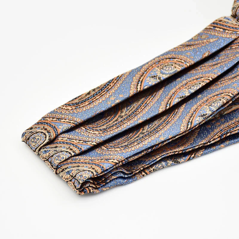 Folded blue tie with intricate brown paisley pattern on white background