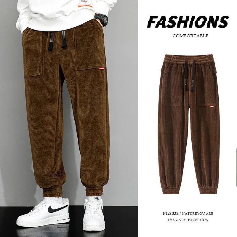 Brown corduroy jogger pants with drawstring waist and elastic cuffs, worn with white sneakers