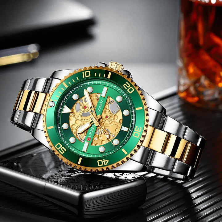 Silver and gold wristwatch with green bezel and intricate gold skeleton dial on a black textured surface