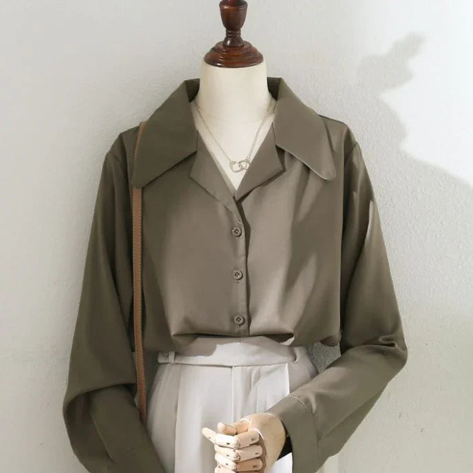 Mannequin wearing olive green button-up blouse with wide collar and beige high-waisted pants