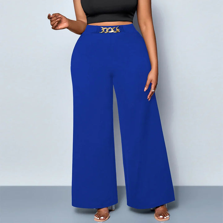 Woman wearing royal blue wide-leg pants with gold chain belt and black crop top