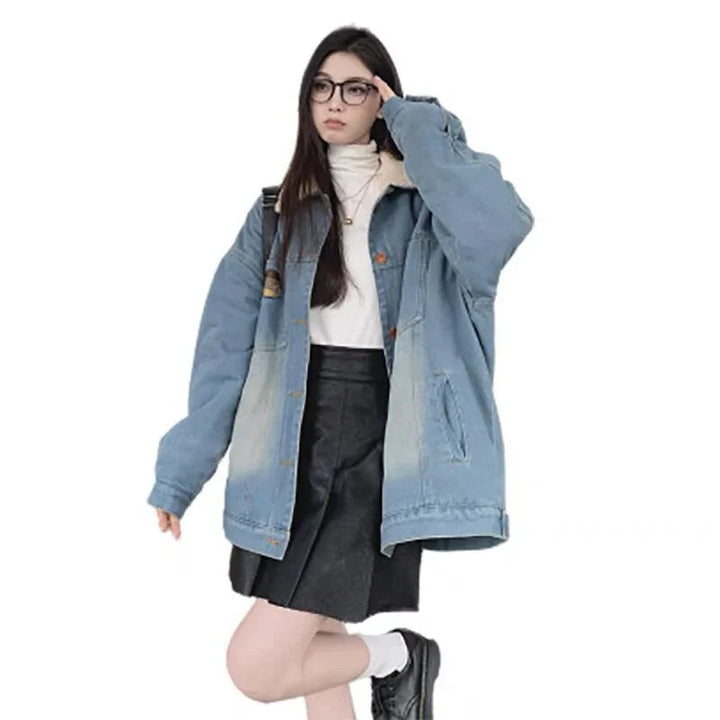 Young woman wearing oversized denim jacket, white turtleneck, black skirt, glasses, and black shoes