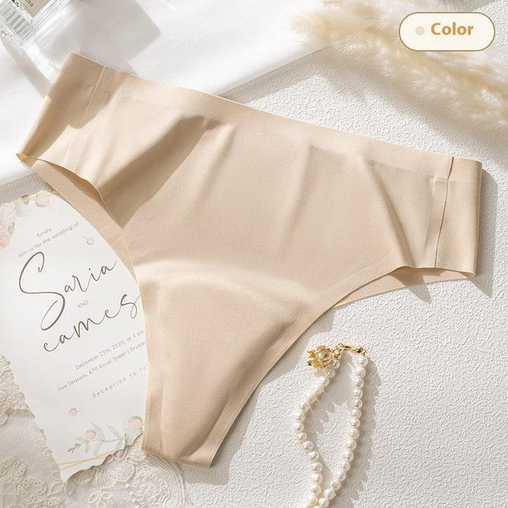 Beige seamless women's underwear with pearl bracelet and wedding invitation on textured white surface