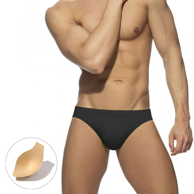 Fit male model wearing black seamless bikini underwear on white background with beige underwear padding detail