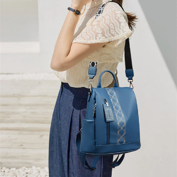 Woman wearing cream lace blouse and blue skirt with stylish blue leather backpack outdoors