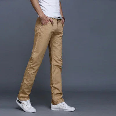 Man wearing beige casual pants and white sneakers against gray background
