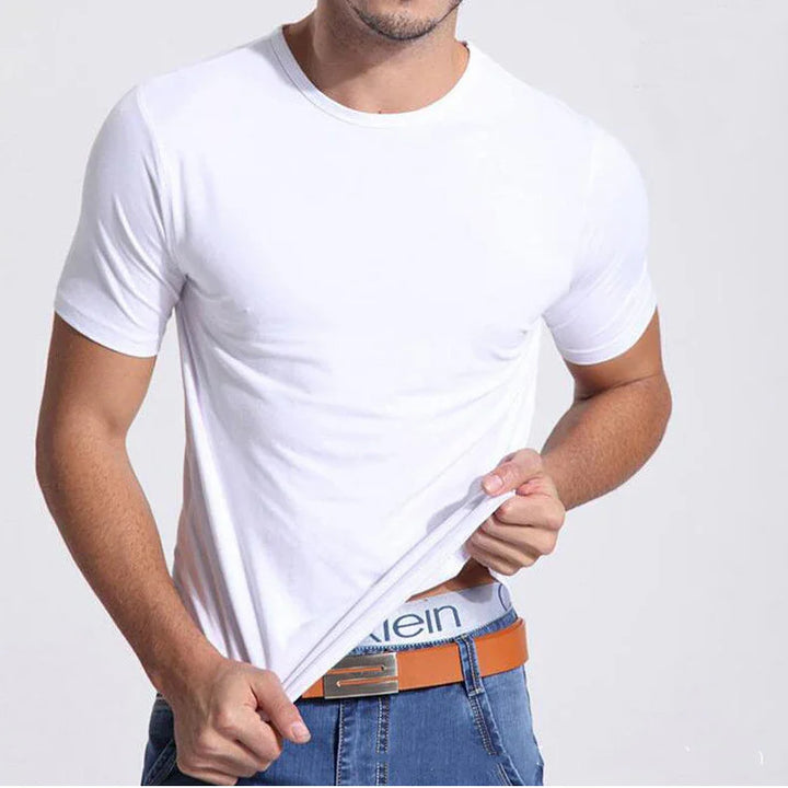 Man wearing plain white t-shirt pulling up shirt hem to reveal Calvin Klein waistband and blue jeans