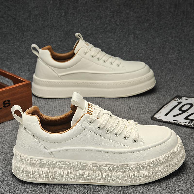 Pair of white leather lace-up sneakers with thick soles and brown inner lining on gray carpet