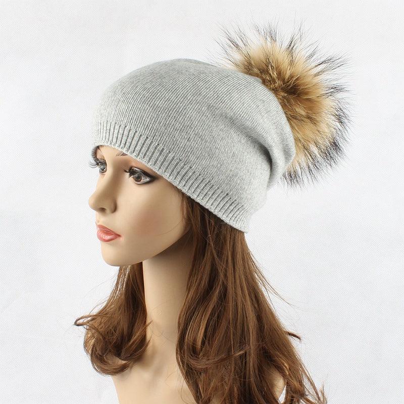 Woman mannequin wearing light gray knit beanie hat with large brown fur pom-pom