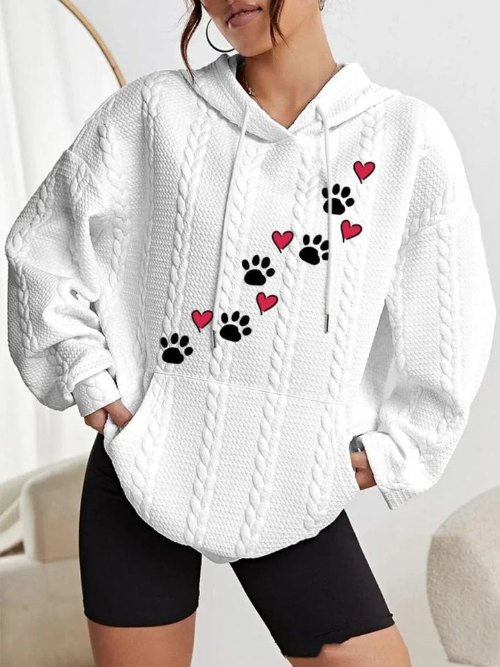 White cable knit hoodie with black paw prints and red hearts design, worn with black shorts