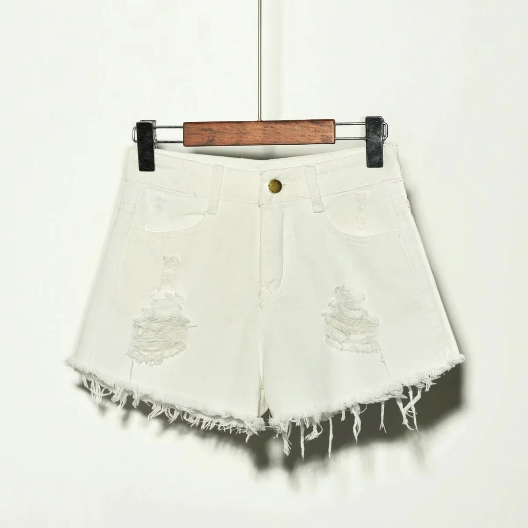 White distressed denim shorts with frayed hem hanging on wooden and metal hanger