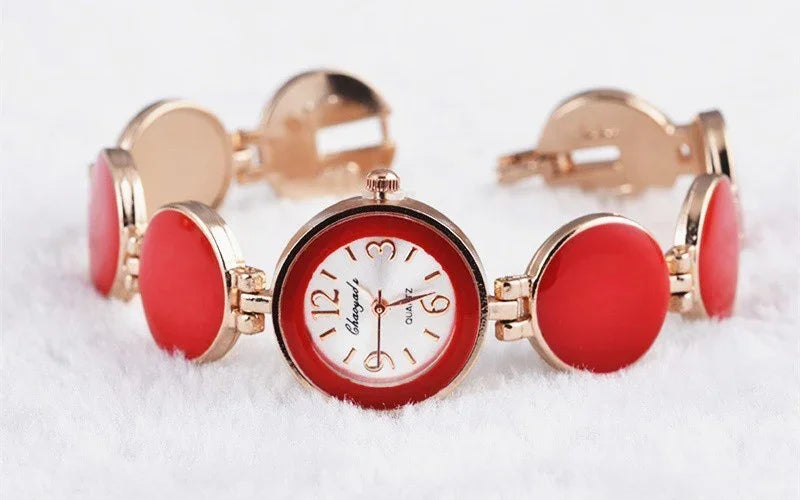 Elegant red and gold ladies wristwatch with circular links on a white textured surface