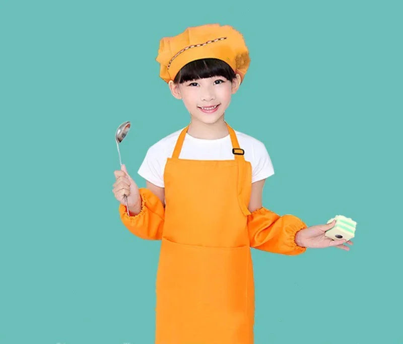 Smiling child chef in orange apron and hat holding a spoon and toy cake against teal background