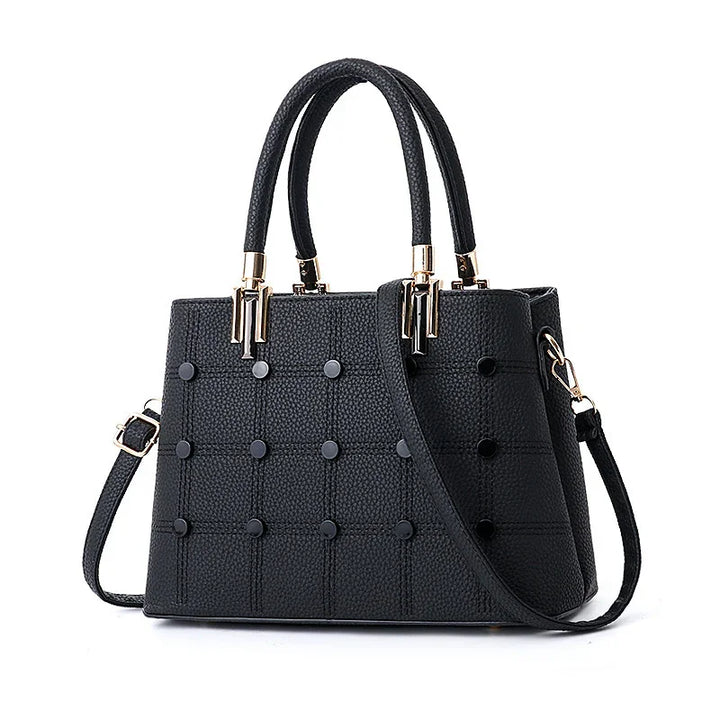 Black textured leather handbag with gold hardware, top handles, and detachable shoulder strap