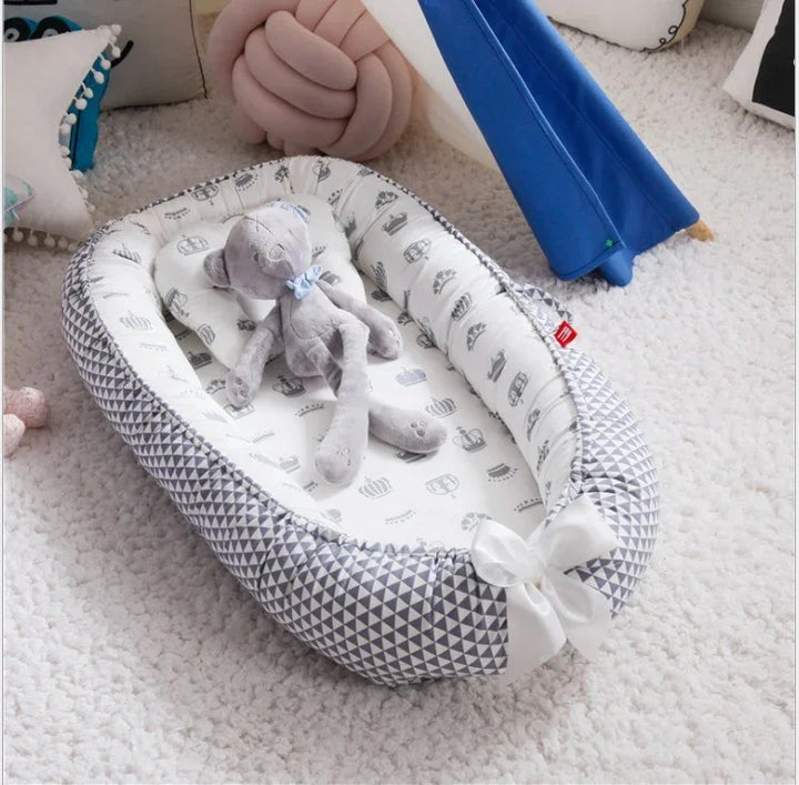 Gray plush teddy bear lying in geometric patterned baby nest on soft white carpet with pillows and blue fabric teepee