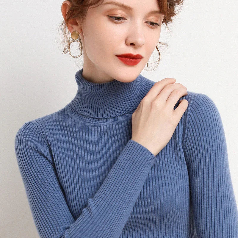 Woman wearing blue ribbed turtleneck sweater with statement gold and chain earrings, red lipstick makeup