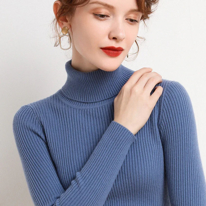 Woman wearing blue ribbed turtleneck sweater with statement gold and chain earrings, red lipstick makeup