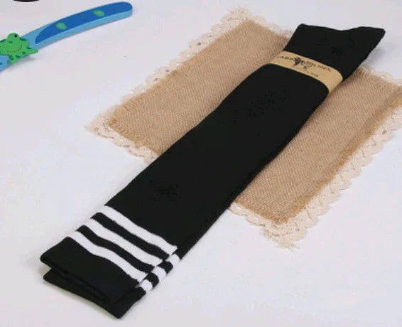Black knee-high socks with white stripes folded on a burlap mat with lace edges on a white surface