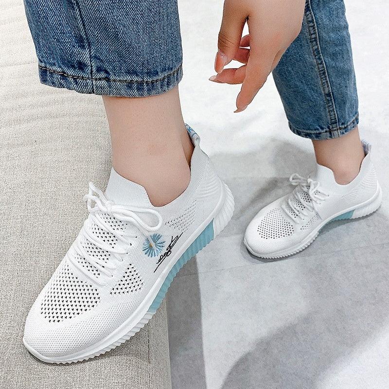 White knitted casual sneakers with blue accents and floral embroidery worn with blue jeans